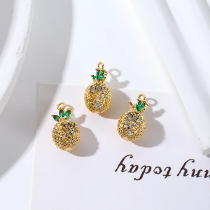 Close-up of gold-plated pineapple charms with sparkling green and white zirconia