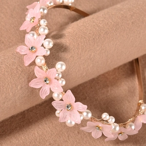 Macro detail of pink matte flowers and white pearls on a gold metal headband