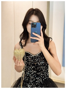 Mirror selfie showing a mini golden heart-shaped evening bag with tassels and rhinestones