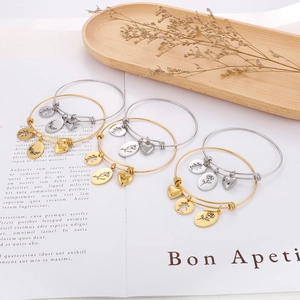 Detailed view of gold and silver charm bracelets with heart and floral pendants on an open book
