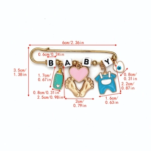 Detailed view of baby themed gold safety pin brooch with enamel charms and size markings