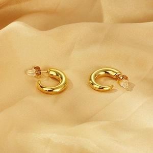 Macro shot of 18K gold plated stainless steel C-shaped hoop earrings on silk fabric