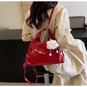 Detail of red PU leather bag featuring a chic bow and a plush cloud charm accessory