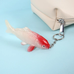 Miniature PVC koi fish keychain with realistic red and white patterns on a blue background