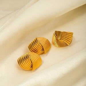 Nahaufnahme von goldenem 18k Edelstahlring und Ohrringen auf beigem Seidenstoff