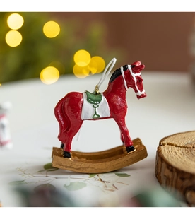 Détail d'un ornement cheval à bascule en résine rouge avec base dorée et décorations