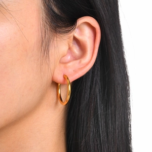 Close-up of model wearing polished 18k gold-plated stainless steel geometric hoop earrings