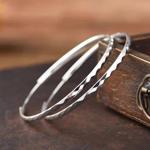 Polished silver hoop earrings with diamond-cut texture on vintage wooden box