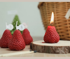 Macro shot of a burning strawberry shaped scented candle on a wooden base for home decor