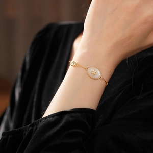 Close-up of a vintage gold bracelet with a zircon star oval pendant on a model's wrist