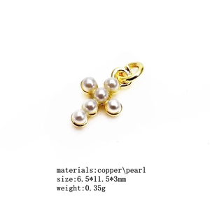 Macro shot of gold-colored copper cross charm pendant set with small white pearls