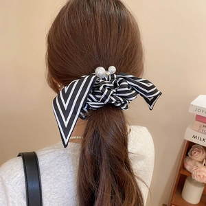 Detailed view of a striped bow scrunchie with pearls and rhinestones on a low ponytail