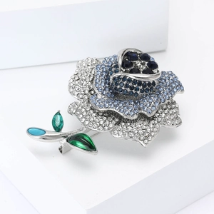 Broche rose élégante avec cristaux bleus et transparents sur métal argenté
