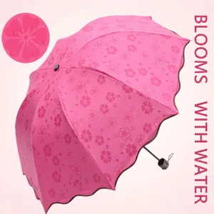 Pink folding umbrella showing floral patterns when wet for rain and sun protection