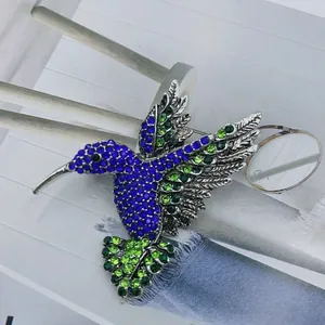 Macro shot of hummingbird brooch featuring vibrant blue and green crystal pavé stones