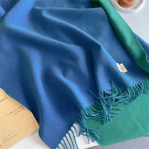 Detail showing blue and green double-sided cashmere scarf texture with tassel edges