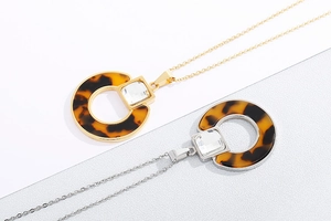 Detail of round tortoiseshell resin pendants with crystal studs in gold and silver plating