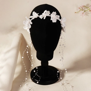 Detailed view of bridal headpiece featuring white fabric flowers and pearl fringe tassels