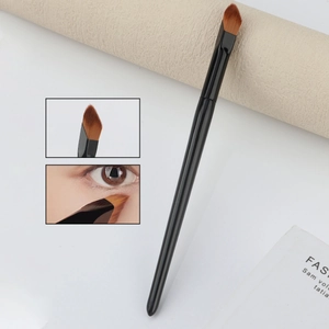 Angled concealer and highlighter brush with synthetic bristles and black handle for makeup