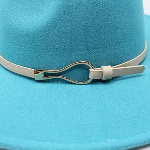 Detail of blue wool felt fedora featuring a slim white leather band and gold metal buckle