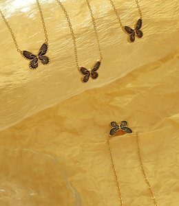 Artistic layout of multiple black butterfly pendants on gold chain with warm lighting