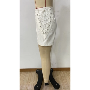 Detail view of white mini skirt featuring lace-up side design with metal eyelets on a mannequin