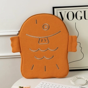 Close-up of orange monster laptop sleeve with embroidered expression and plush texture