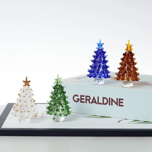 Detailed view of four handmade glass Christmas trees with gold stars in various colors