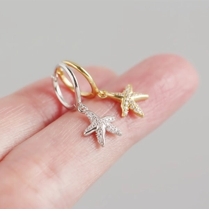 Macro shot of S925 sterling silver starfish earrings with zircon pavé on a finger