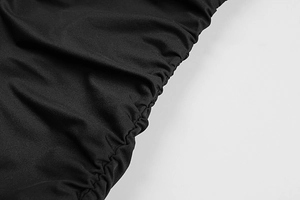 Detail view of the black ruched fabric texture and split hem stitching on a summer dress