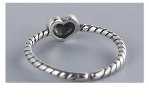 Macro detail of S925 sterling silver heart ring featuring a twisted rope band design