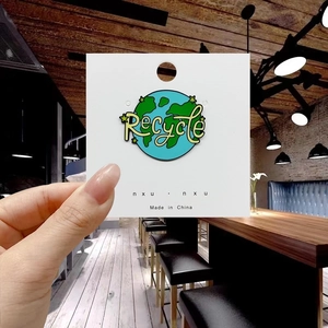 Detail of round Recycle Earth enamel pin featuring blue oceans and green continents