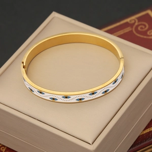 Detail of golden evil eye bangle with white enamel inlay and hinge closure mechanism