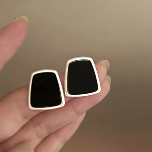 Detail of geometric silver resin stud earrings with black glossy finish and metallic edge