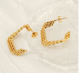 Détail des boucles d'oreilles torsadées en métal doré 18K avec une forme en C carrée
