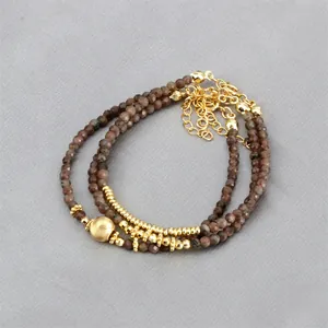 Detail of layered beaded bracelet with brown faceted stones and gold plated metal beads
