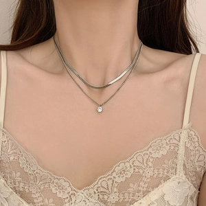 Close-up of double layer silver snake chain necklace with a round zircon pendant on neck