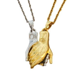 Golden and silver couple necklaces with praying hand pendants on clean white background