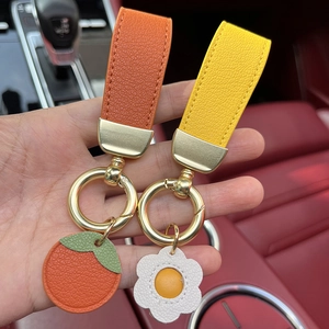 Creative handmade leather keychain featuring orange fruit and white daisy with gold ring