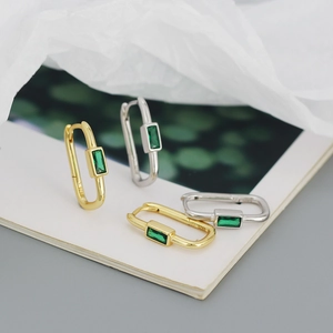 Detail of S925 silver stamp on gold and silver U-shaped earrings with green zircon