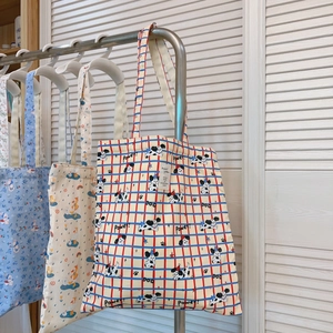 Detailansicht der cremefarbenen Canvas-Tasche mit rot-blauem Gitter und Hunde-Illustrationen