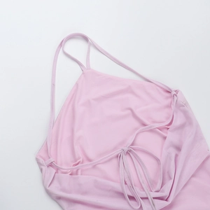 Flat lay detail of pink halter dress showing backless lace-up design and fabric texture