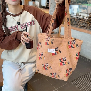 Detail of beige corduroy tote bag showing metal snap button closure and smiley patterns