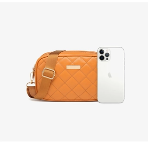 Macro shot of orange quilted camera bag with adjustable strap and smartphone for scale