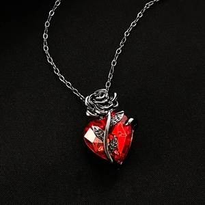 Gothic heart necklace with red faceted gemstone and silver rose details on black background