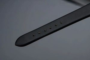 Close-up of black leather watch strap featuring seven adjustable holes for fit