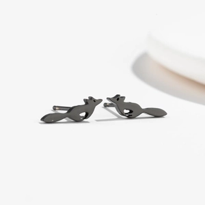 Macro shot of minimalist matte black running fox stud earrings on white surface