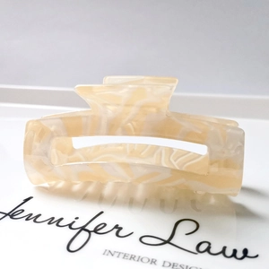 Detail of 8.3cm cream acetate hair claw with marbled texture and hollow rectangle design