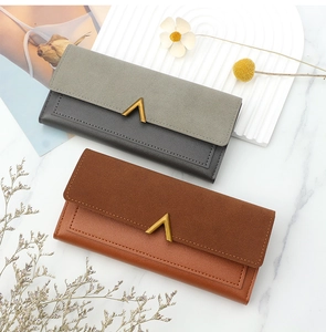 Detail of long PU leather wallets with V-shaped metal buckles on marble surface