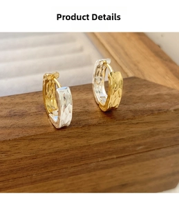 Detailed view of hammered metal huggie earrings with gold and silver two-tone texture